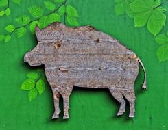 wooden figurine of a wild boar on a green background