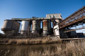 Landscape with the chemical plant, among the plants, near the water, at blue sky on background