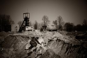 Black and white photo of the coal mining site, with the machine, among the trees