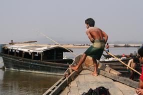 asian boys fishing from boats at coast