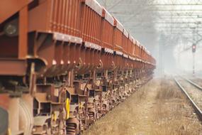 Orange, metal train on the railway, in fog