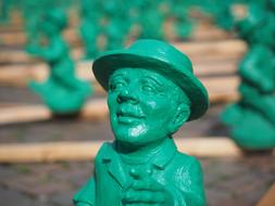 Green figure of a man in hat, among the other figures in Frankfurt, Germany