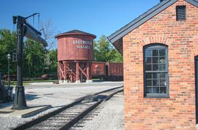 Rail yard with the colorful brick building, near the green trees in USA, at blue sky on background