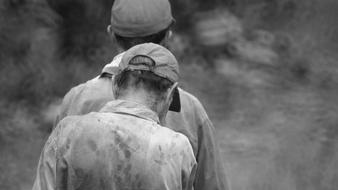 Black and white photo with the back view of the men in hats, at blurred background