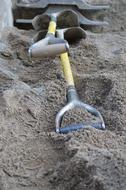 Shiny shovels, with the metal handles, in the sand