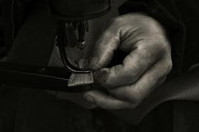 dirty male hand with leather at sewing machine