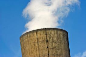 Industrial tower with white smoke, at blue sky with white clouds on background