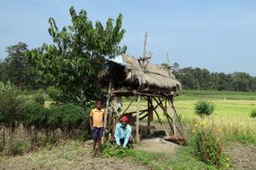 two man beneath shed in countryside, india