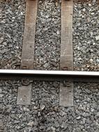 Close-up of the shiny, metal track of the rail, among the stones