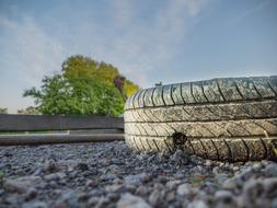 Old auto tires, among the rocks, near the colorful trees, under the blue sky with clouds