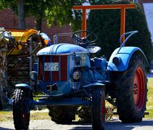 Close-up of the blue "Hanomag" tractor with black and red wheels, in light