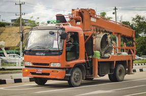 Orange truck, on the road, among the hills, under the cloudy sky, on the landscape