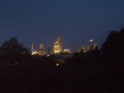 Landscape with the industrial plant, with the lights, among the darkness, at beautiful, blue sky on background, in the evening