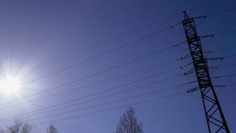 Electricity wires, near the beautiful trees, at blue sky with sunlight
