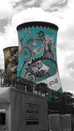 Cooling towers of the nuclear power plant, decorated with beautiful, colorful and patterned graffiti, among the black and white cityscape