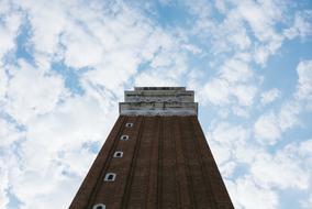 Low angle shot of the brick tower, under the blue sky with white clouds