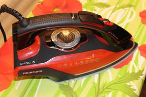 red black iron on an ironing board close up