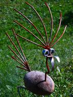 Close-up of the cute and beautiful bird, made with the metal wire, on the green grass, in light