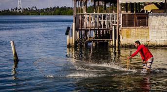 fisherman with nets in the water near the shore