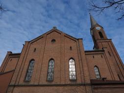 Beautiful Peter Church in New Ulm, with the windows and tower, near the trees, under the blue sky with white clouds