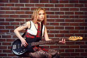 Photo of guitarist girl on brick wall background