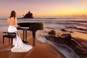 Woman in white dress, playing on piano on the beautiful sandy beach with rocks, at colorful sunset in the sky