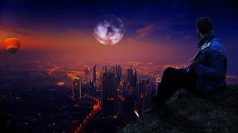 man on a rock against the background of the city at dusk