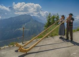 couple playing Alphorn in mountains
