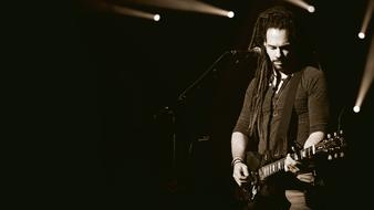 musician with a guitar near the microphone on stage in monochrome