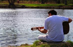 man plays Guitar at water