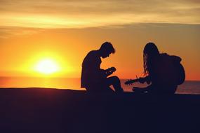 young Musicians, two Guitarists at sunset sky