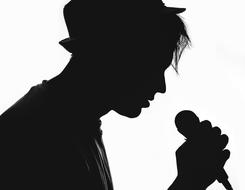 black silhouette of a musician in a hat with a microphone