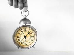 Black and white photo of the beautiful, vintage, metal clock with Roman numerals in the hand