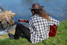 guitarist on the grass above the water