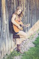 girl with guitar near old wooden fence