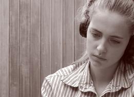 Black and white portrait of the girl, listening to music, with the headphones, near the wall