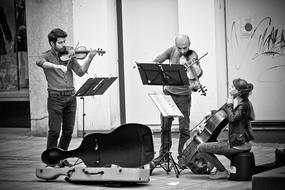 Black and white photo of the street musicians, playing on the different musical instruments, on the street