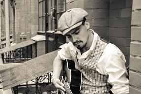 street musician with a guitar in a plaid cap