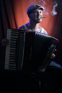 Musician in hat, playing on the accordion and smoking a cigarette