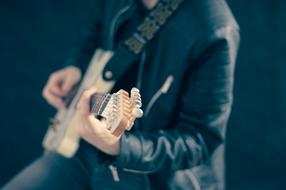 Man in black jacket, playing on the electric guitar