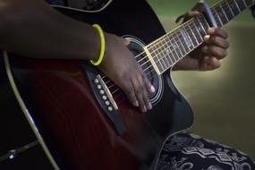 dark skin woman plays acoustic Guitar