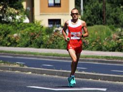 Person in red and white clothing, running on the road, among the colorful plants