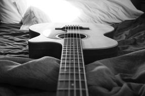 black and white photo of a guitar on the bed