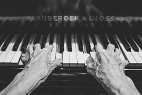 black and white photo of the hands of an elderly musician on the piano keys