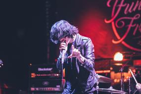 Singer in the jacket, signing on the stage, with the colorful lights