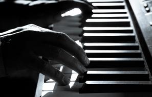 musician's hands on piano keyboard, black and white