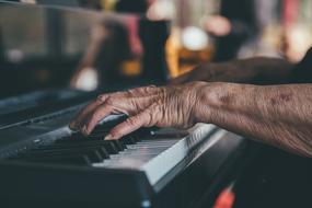 hands of an elderly man on the piano keys