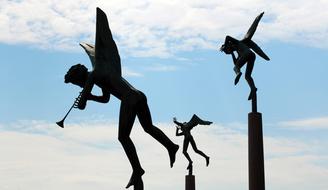 Beautiful statues of the angels, at background with blue sky with white clouds