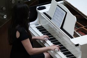 woman playing white piano