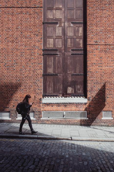 walking person near the brick wall